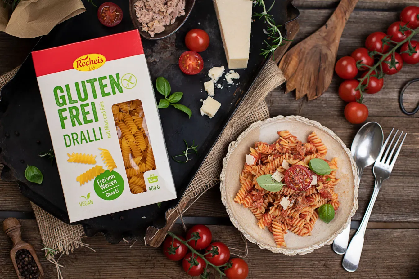 Glutenfreie Nudeln mit Thunfisch-Tomatensauce, Käse und frischen Tomaten auf Holztisch