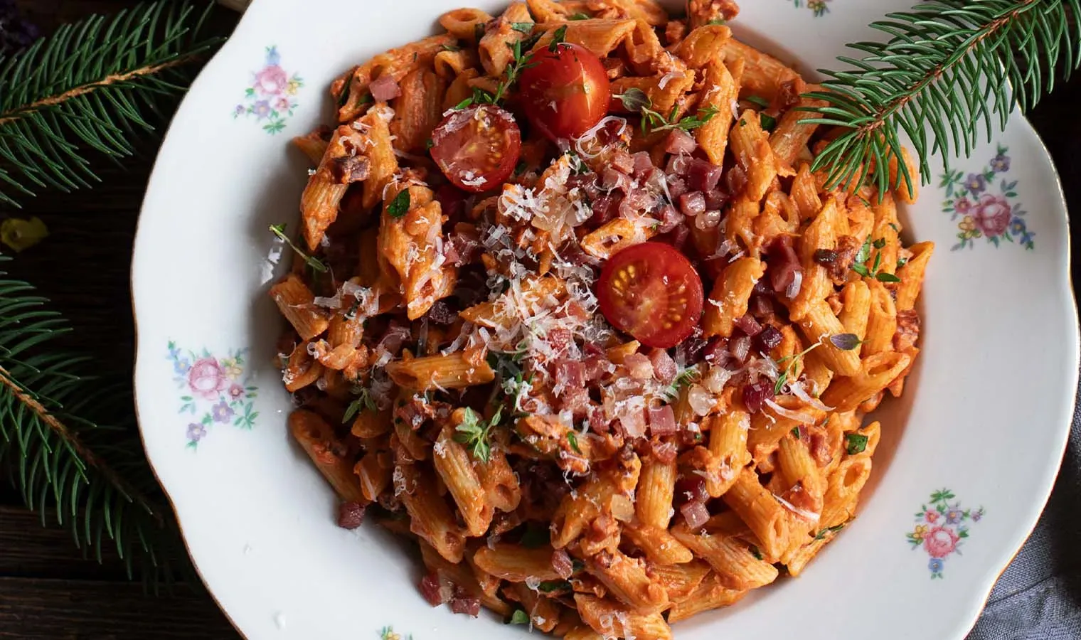 Nudeln mit Tomaten-Sahne-Speck-Sauce, garniert mit geriebenem Käse, auf einem Teller