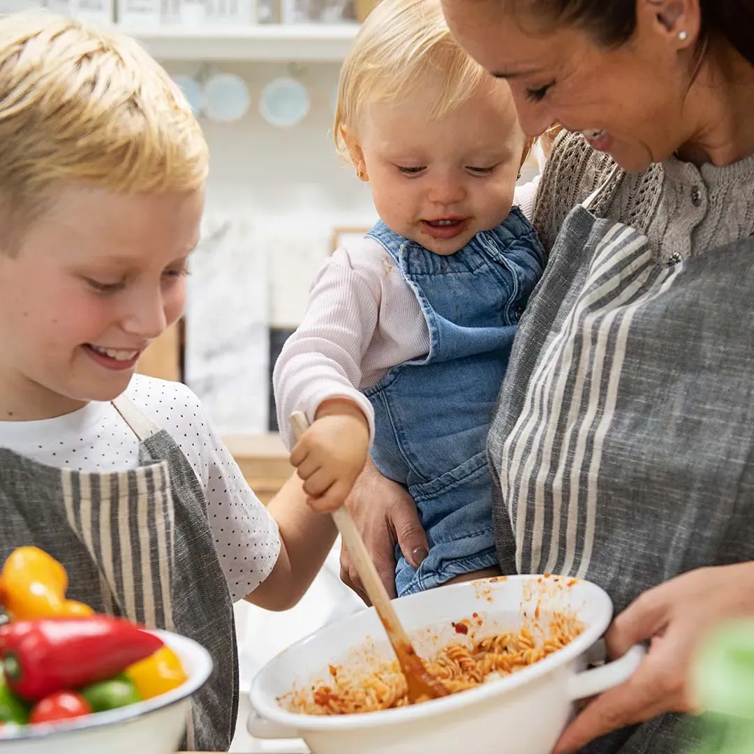 Frau und zwei Kinder rühren gemeinsam in einer Schüssel Nudeln mit Tomatensauce