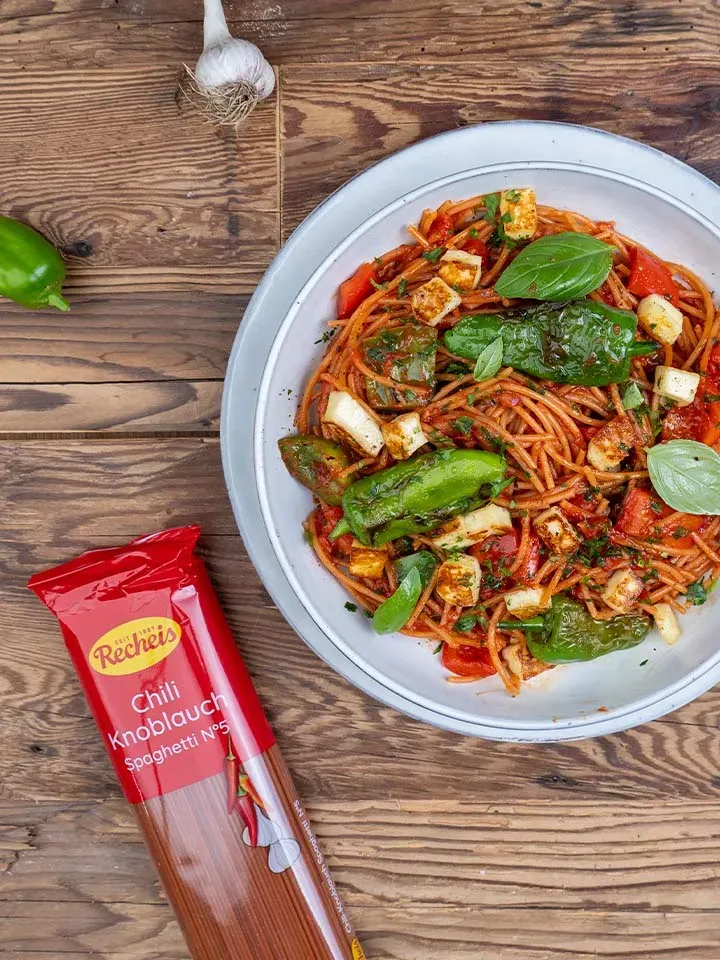 Chili-Knoblauch-Spaghetti mit Pimientos de Padrón und frischen Zutaten auf einem Teller auf Holztisch