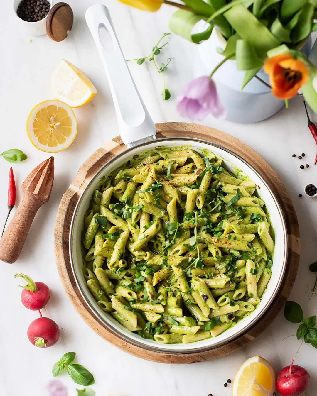 Nudelpfanne mit Bärlauch: Penne in grüner Sauce in der Pfanne, umgeben von Zitronen und frischen Kräutern