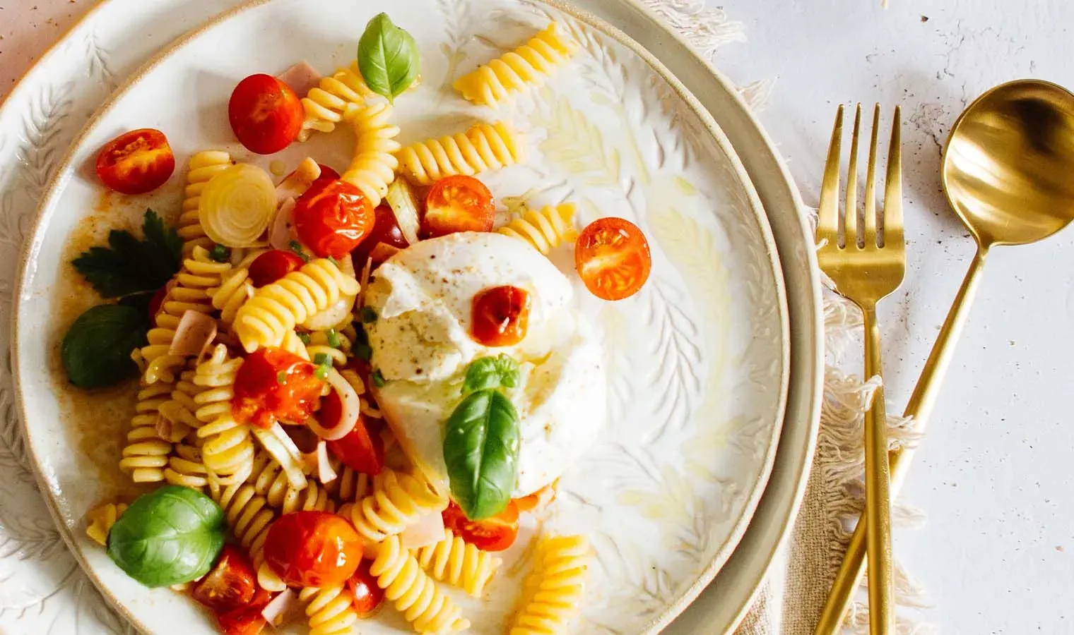 Nudelpfanne mit Osterschinken und geschmolzenen Tomaten, Fusilli mit Basilikum und Mozzarella auf Teller