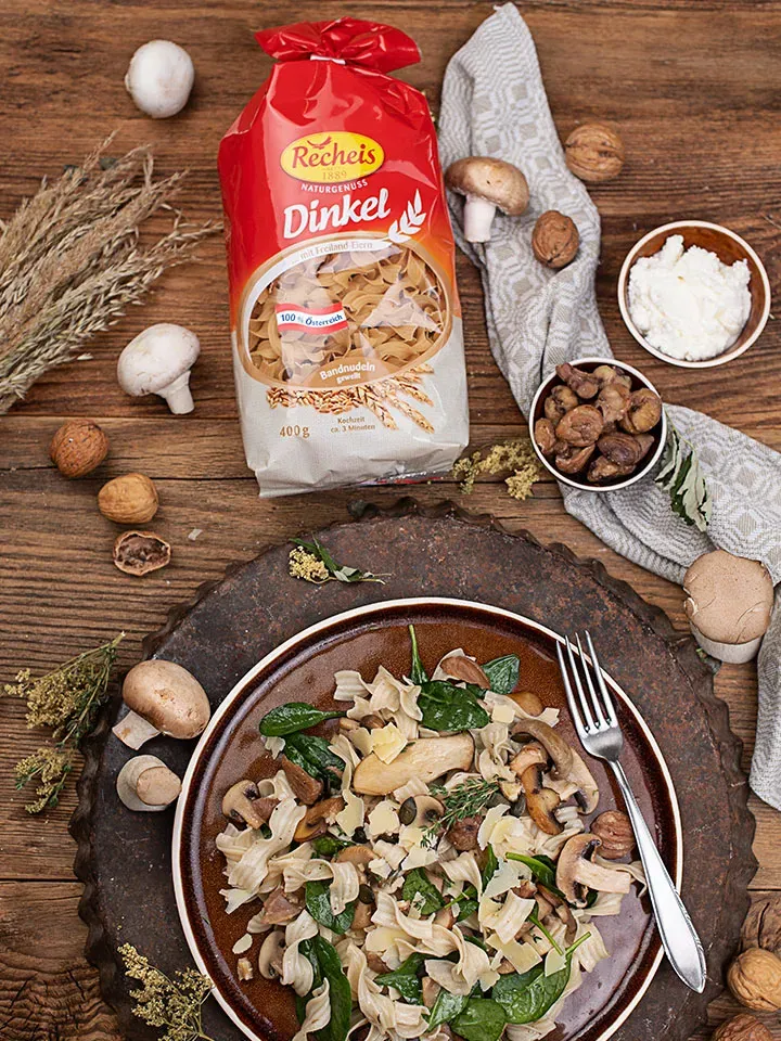 Nudelpfanne mit Pilzen und Maroni: Dinkelbandnudeln mit Spinat neben Dinkelnudelpackung und Zutaten