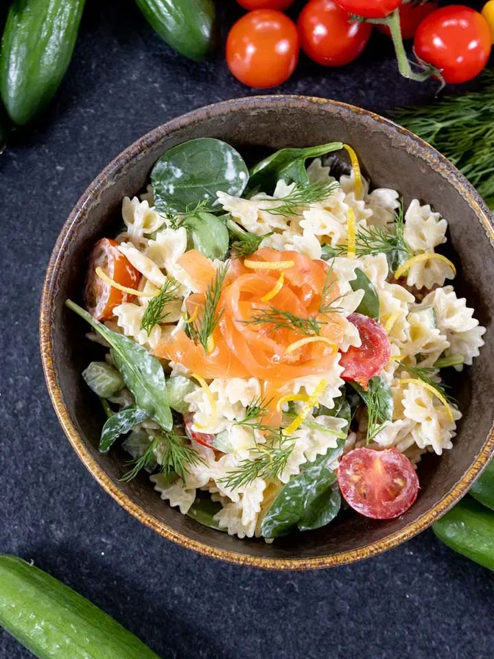 Nudelsalat mit Farfalle, Lachs, Spinat, Tomaten und Dill in einer Schüssel