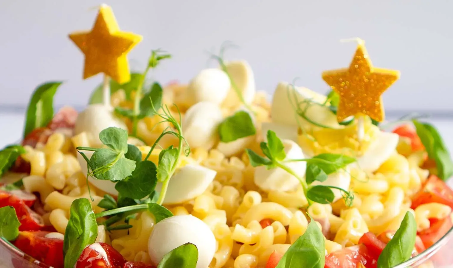 Nahaufnahme der Nudelsalattorte mit Tomaten, Mozzarella, Kräutern und Sterndekoration