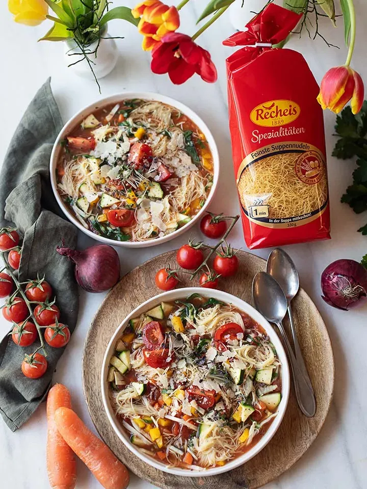 Nudelsuppe zum Mitnehmen: zwei Schalen Gemüsesuppe mit Suppennudeln und frischem Gemüse auf dem Tisch