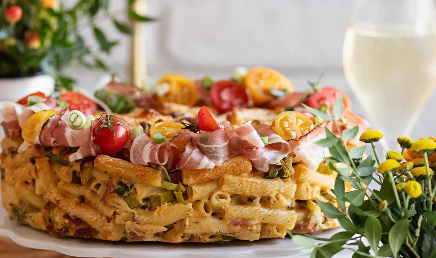 Herzhafte Nudeltorte mit Schinken, Tomaten und Frühlingszwiebeln dekoriert