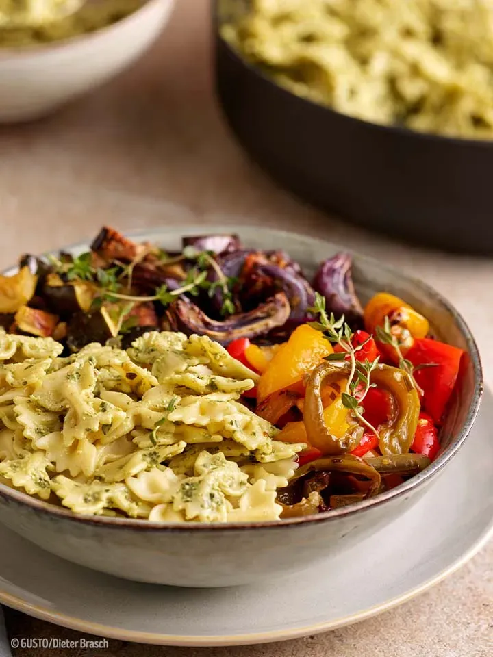Farfalle mit Ofengemüse in einer Schüssel, mit Kräutern garniert