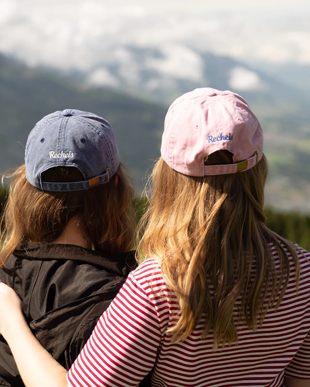 Zwei Personen mit Baseballkappen schauen in eine Berglandschaft