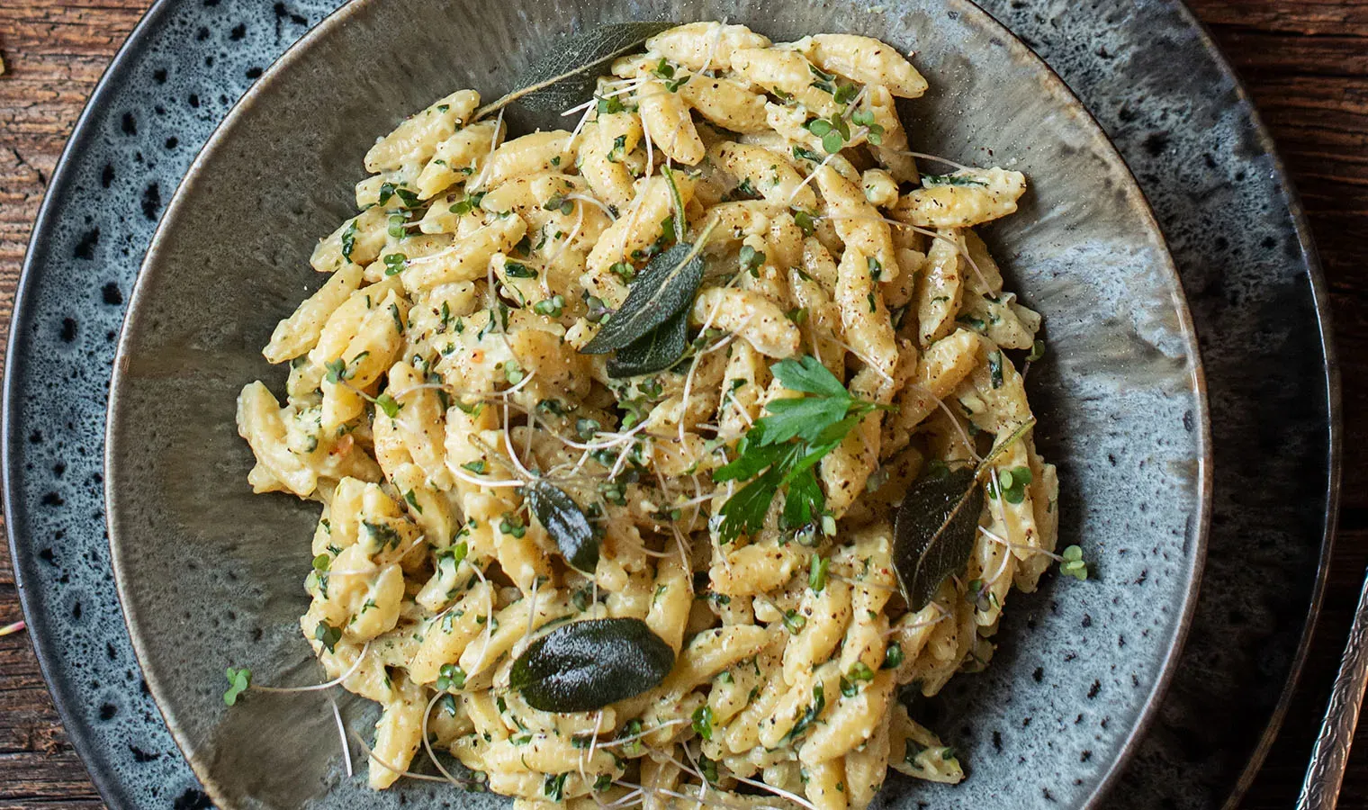 One-Pot-Nudelpfanne mit Kräutern in Nahaufnahme: cremige Pasta mit frischen Kräutern auf Holztisch