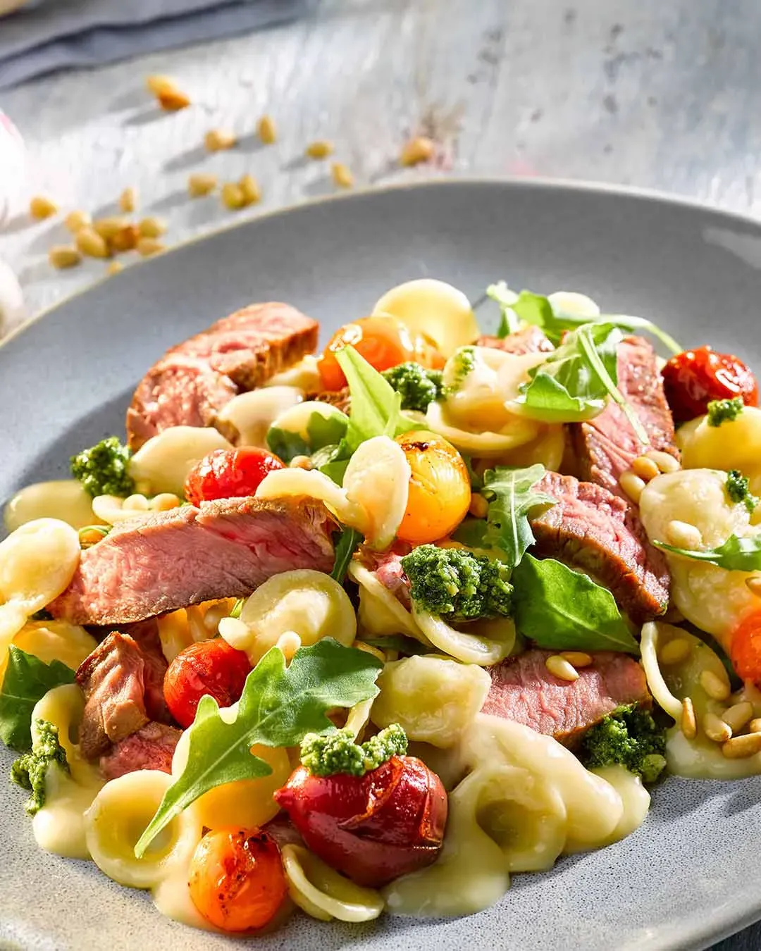 Orecchiette Tagliata di Manzo: Teller mit gegrilltem Steak, Kirschtomaten, Rucola und grünem Pesto