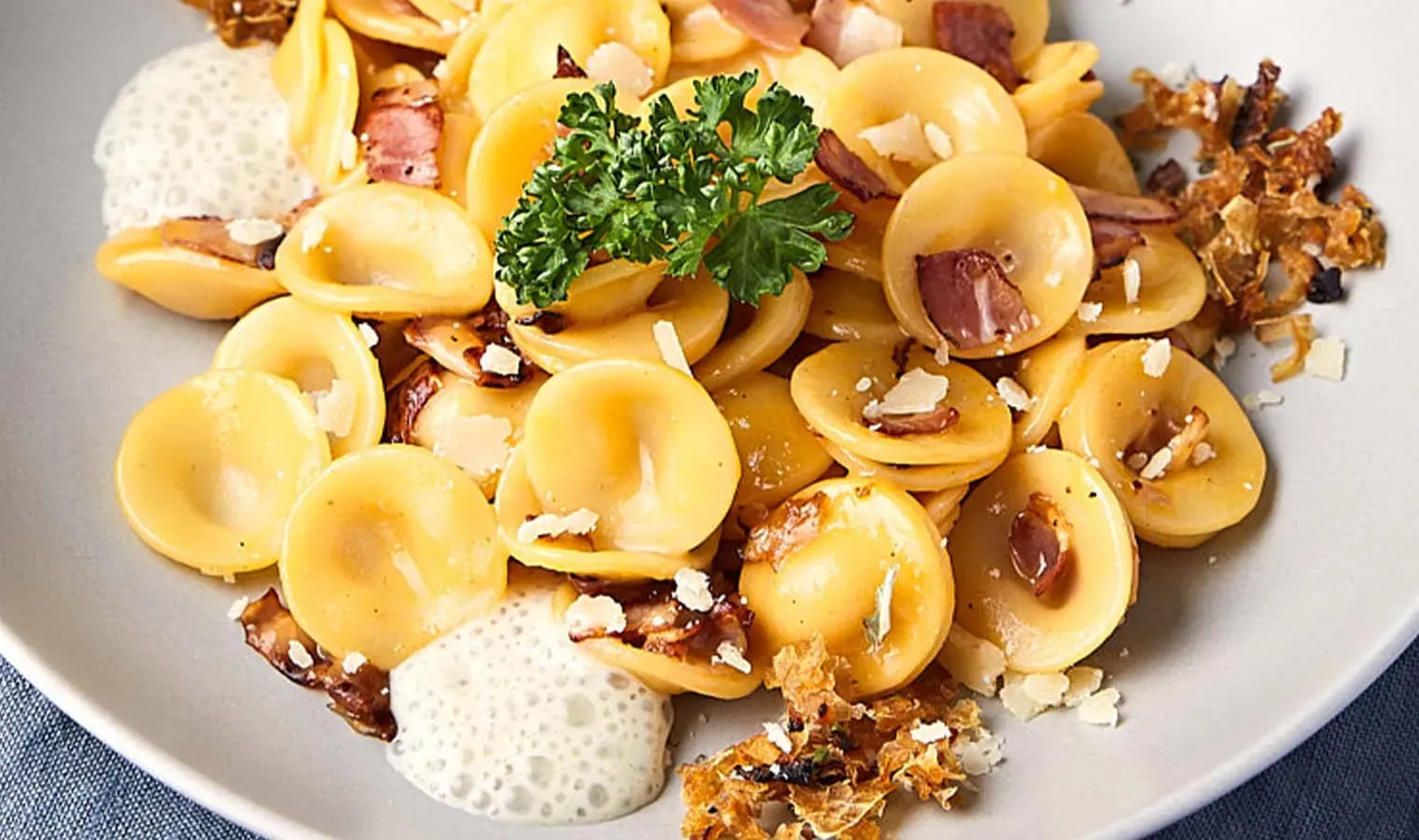 Nahaufnahme Orecchiette Carbonara mit Speck, Schaum und Petersilie