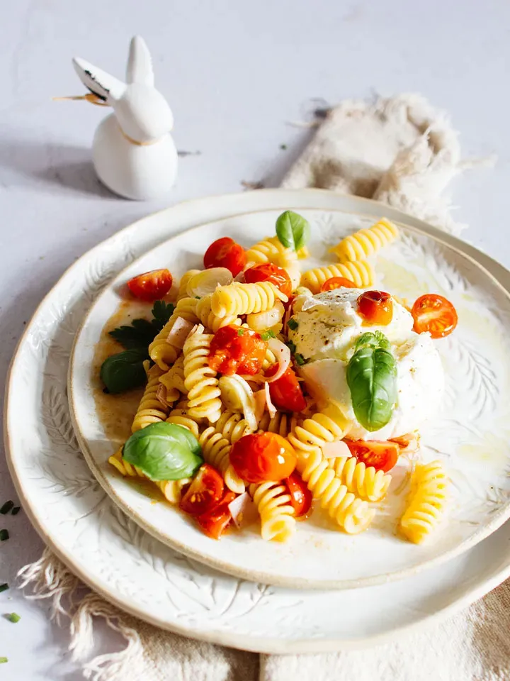 Osterrezept mit Nudeln und Osterschinken: Teller mit Fusilli, Kirschtomaten, Basilikum und Mozzarella