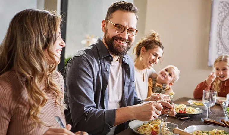 Papas Lieblingsspaghetti: Familie isst gemeinsam am Tisch und lacht