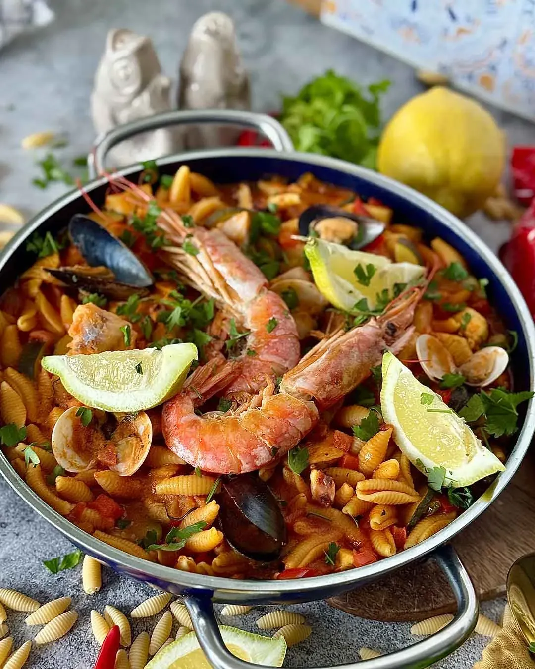 Pasta-Paella mit Meeresfrüchten in der Pfanne, mit Zitronenscheiben garniert