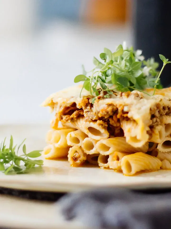Nahaufnahme von Pastizio mit Emmer-Makkaroni, Hackfleisch und frischen Kräutern auf einem Teller
