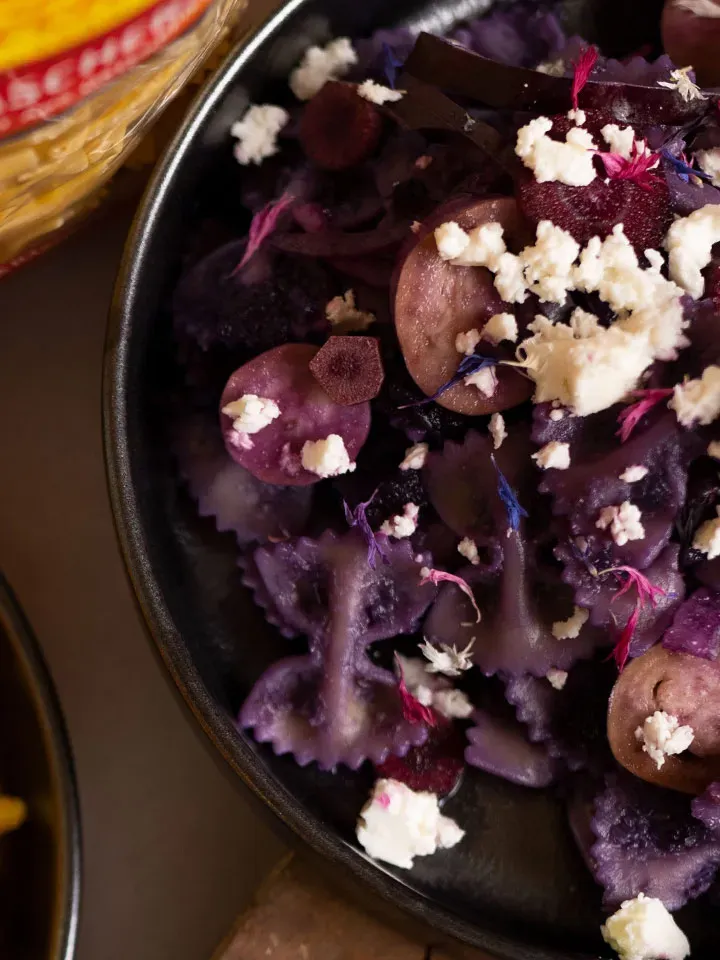 Purple Pasta: Schüssel mit lila Ravioli, mit Käse und essbaren Blüten garniert