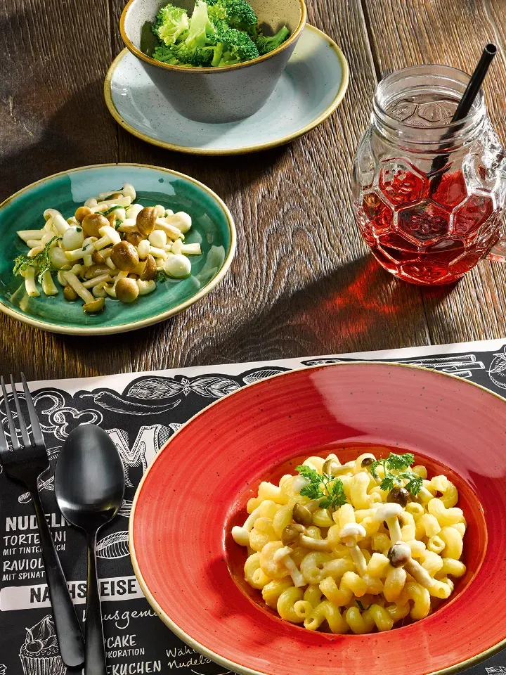 Dinkel-Hörnle mit Parmesansauce und Pilzen, daneben Schalen mit Brokkoli und Pilzen und ein Glas mit rotem Getränk