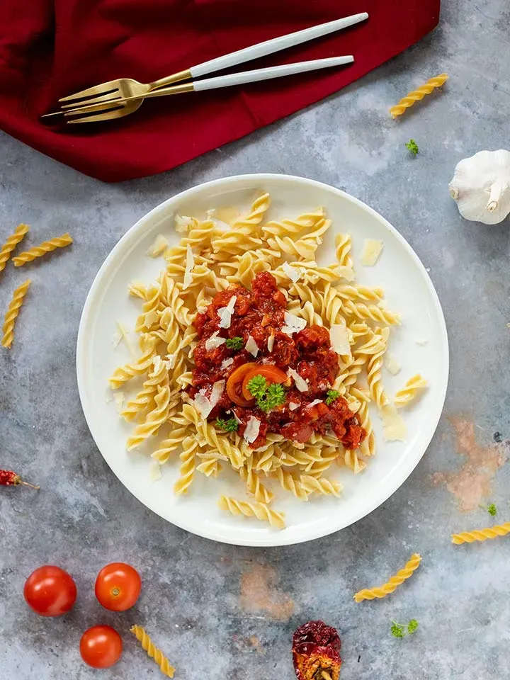 Low-Carb-Fusilli mit scharfer Arrabbiata-Tomatensauce, Parmesan und Petersilie auf grauem Untergrund