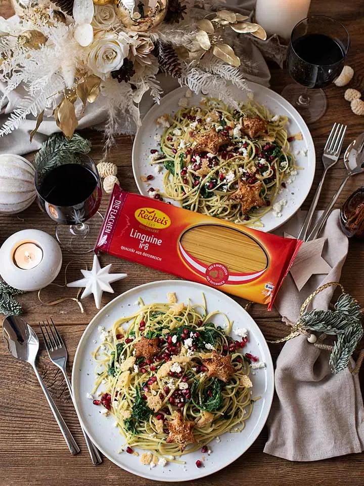 Zwei Teller Linguine mit Granatapfelkernen und Weihnachtsdeko auf Holztisch