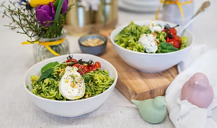 Nudelbowl mit Bärlauchpesto: zwei Schalen grüner Nudelsalat mit Burrata auf gedecktem Tisch