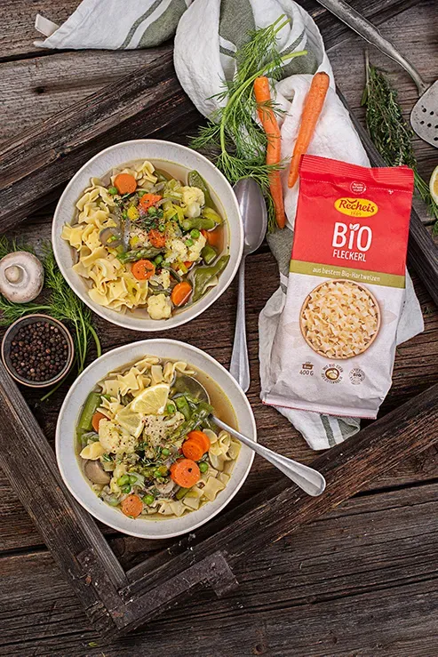 Nudel-One-Pot mit Frühlingsgemüse und Bio Fleckerl: zwei Schalen Suppe auf Holztablett