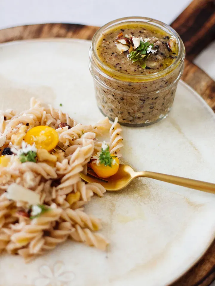 Nudeln mit Aronia-Nuss-Pesto auf Teller, dazu ein kleines Glas mit Pesto