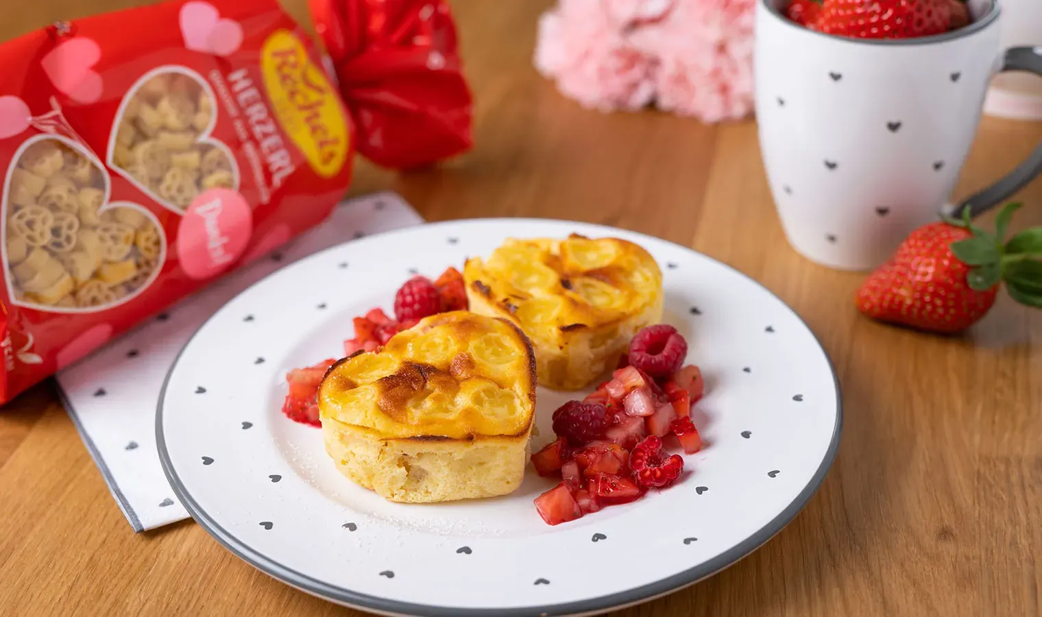 Süße Nudeln als herzförmige Muffins mit Beeren auf einem Teller mit Herzmuster