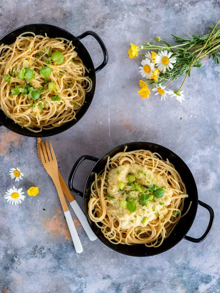 Vegane Pasta Alfredo mit Blumenkohlsauce: zwei schwarze Schalen Spaghetti mit Kräutern und Blumen