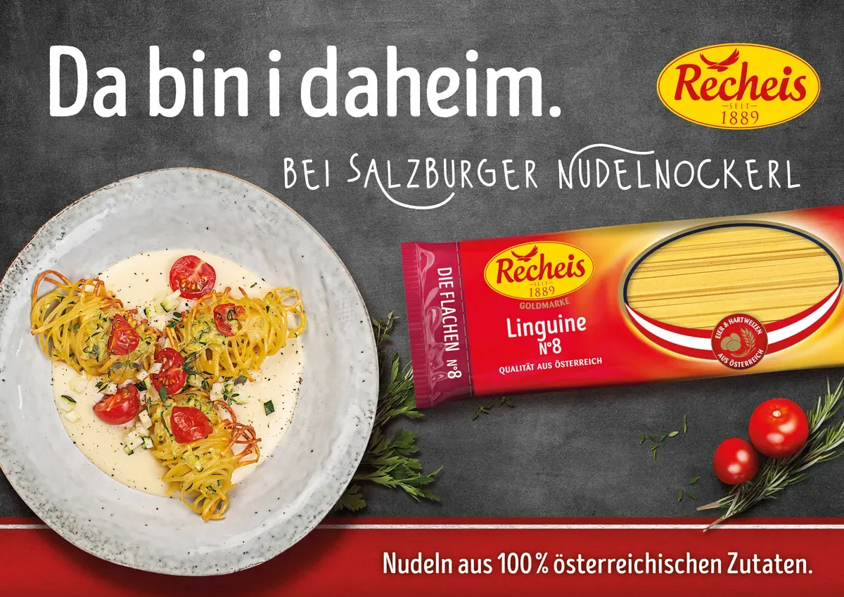 Salzburger Nudelnockerl mit Tomaten auf einem Teller neben einer Packung Recheis Linguine auf dunklem Hintergrund
