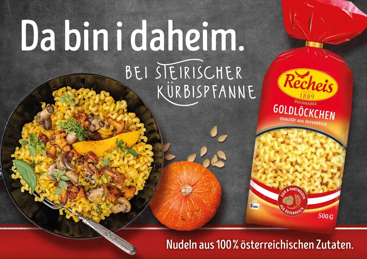 Steirische Kürbispfanne in einer Schale, daneben eine Packung Recheis Goldlöckchen auf dunklem Untergrund