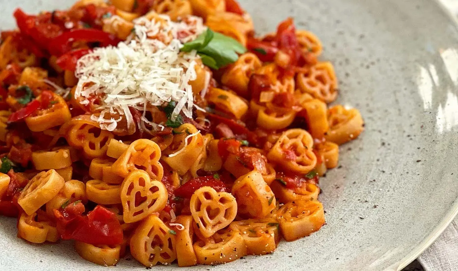 Sugo all'Amatriciana mit herzförmiger Pasta und geriebenem Käse auf einem Teller