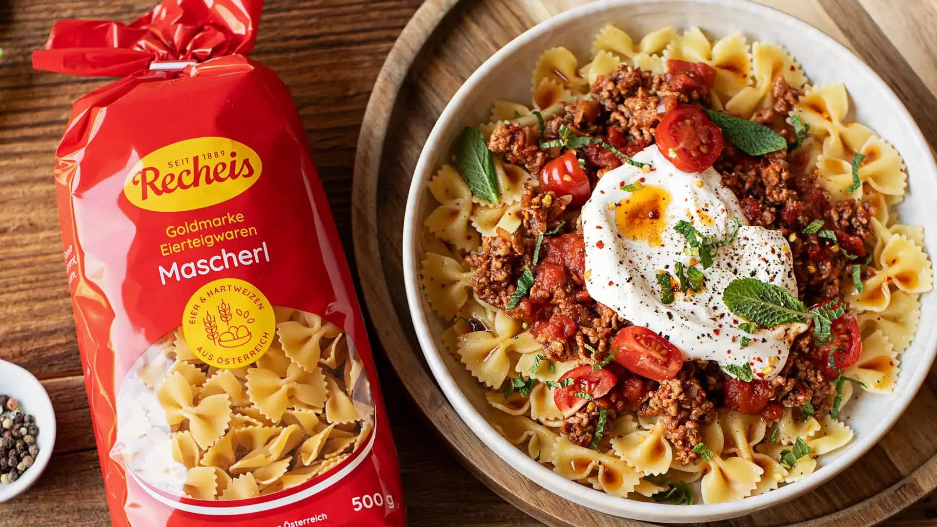 Türkische Pasta mit Farfalle, Hackfleischsoße und einem Klecks Joghurt, daneben eine Packung Mascherl