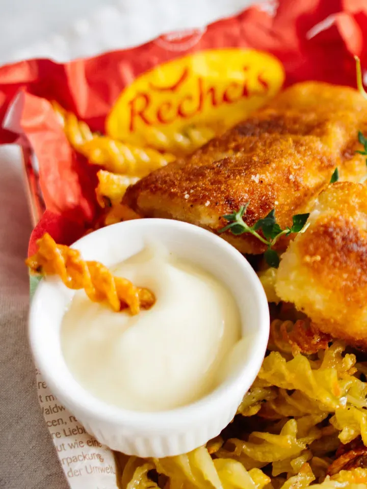 Panierte Fischfilets mit Nudelchips und Mayonnaise in einem roten Behälter