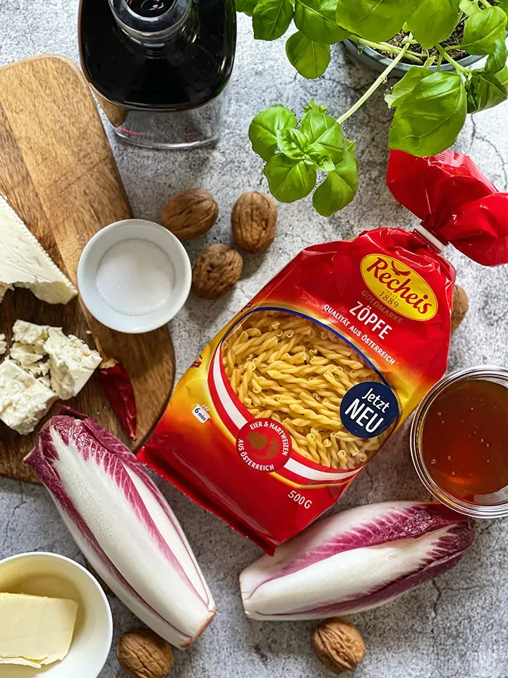 Zutaten für Rotweinnudeln (Drunken Pasta): Pasta, Salat, Nüsse und Kräuter auf einem Tisch