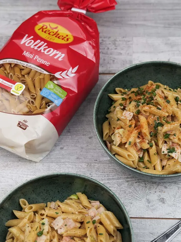 Schinken-Lauch-Nudeln mit Vollkorn-Mini-Penne in Schalen neben der Packung auf Holztisch