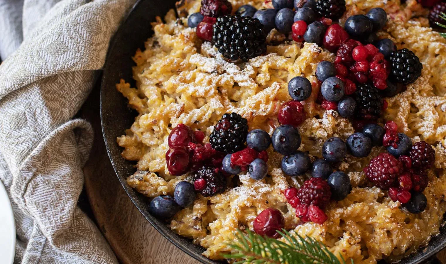 Schmarren mit Nudeln, mit Puderzucker und frischen Beeren in einer Pfanne