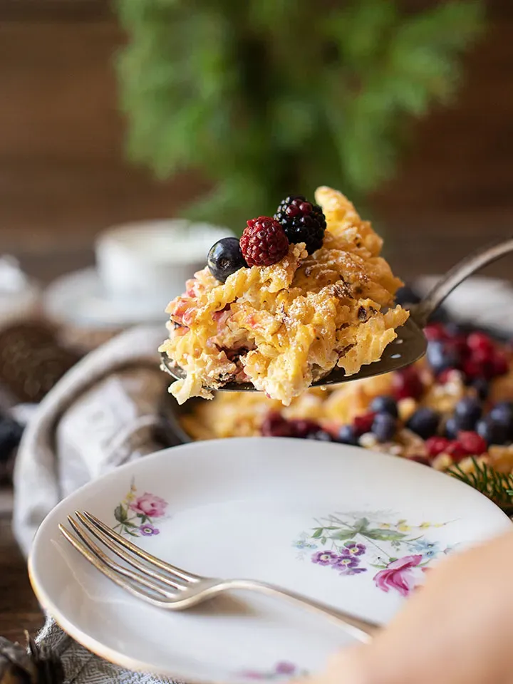 Löffel mit Nudelschmarrn und Beeren über einem Teller mit Gabel
