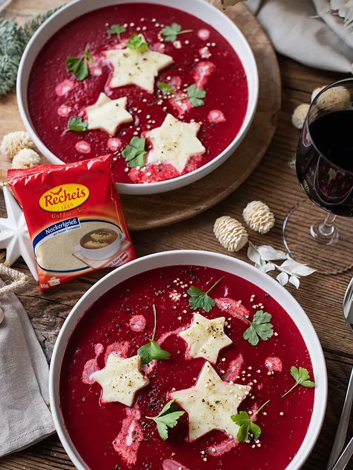 Schöberl-Sterne: rote Suppe mit sternförmigen Einlagen und Petersilie auf Holztisch