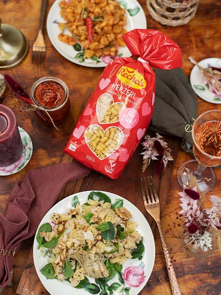 Selbstgemachtes Pesto: Tisch mit zwei Pastagerichten und roter Packung Recheis Herznudeln