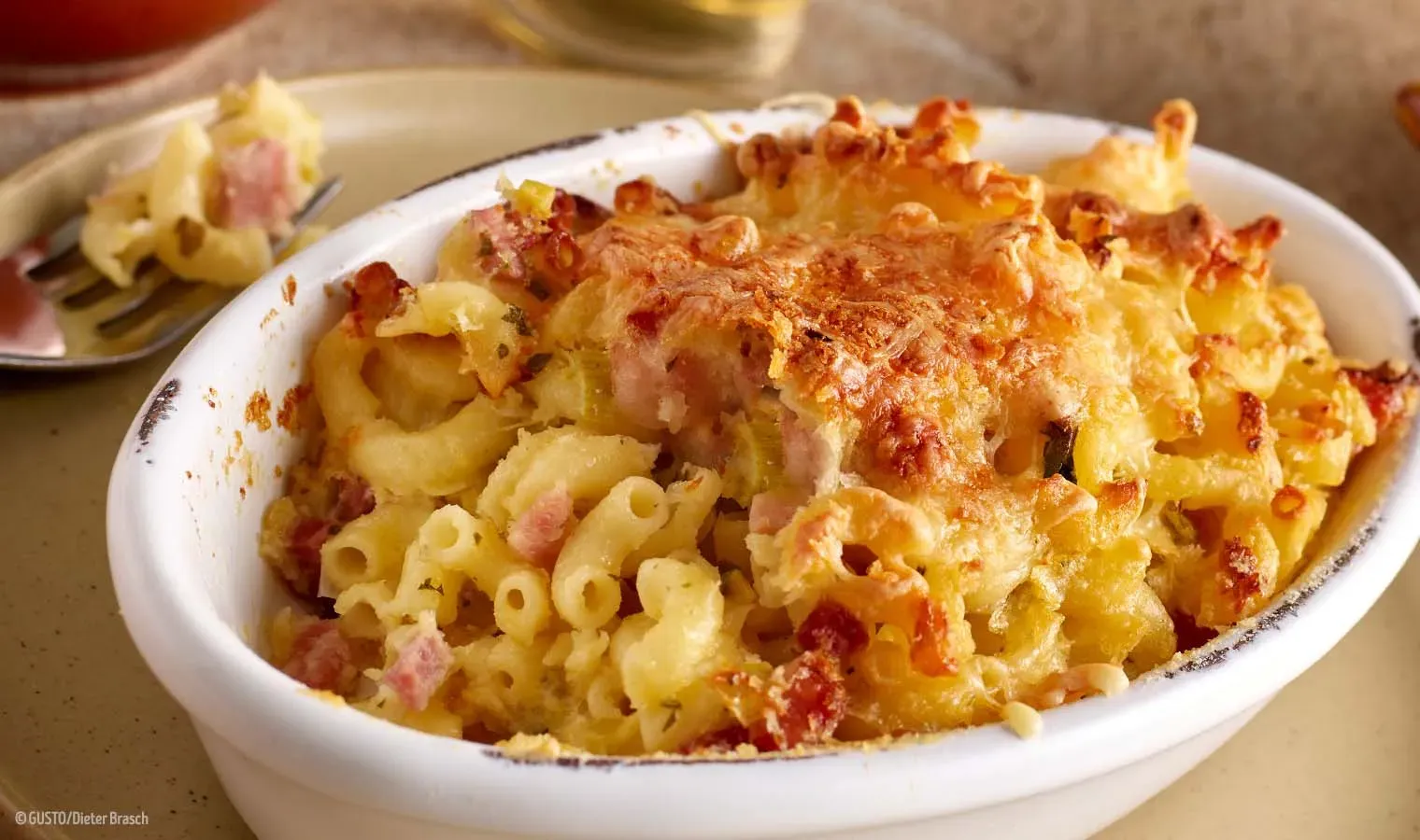 Überbackene Selchfleischnudeln mit Käse und Schinken in einer weißen Auflaufform