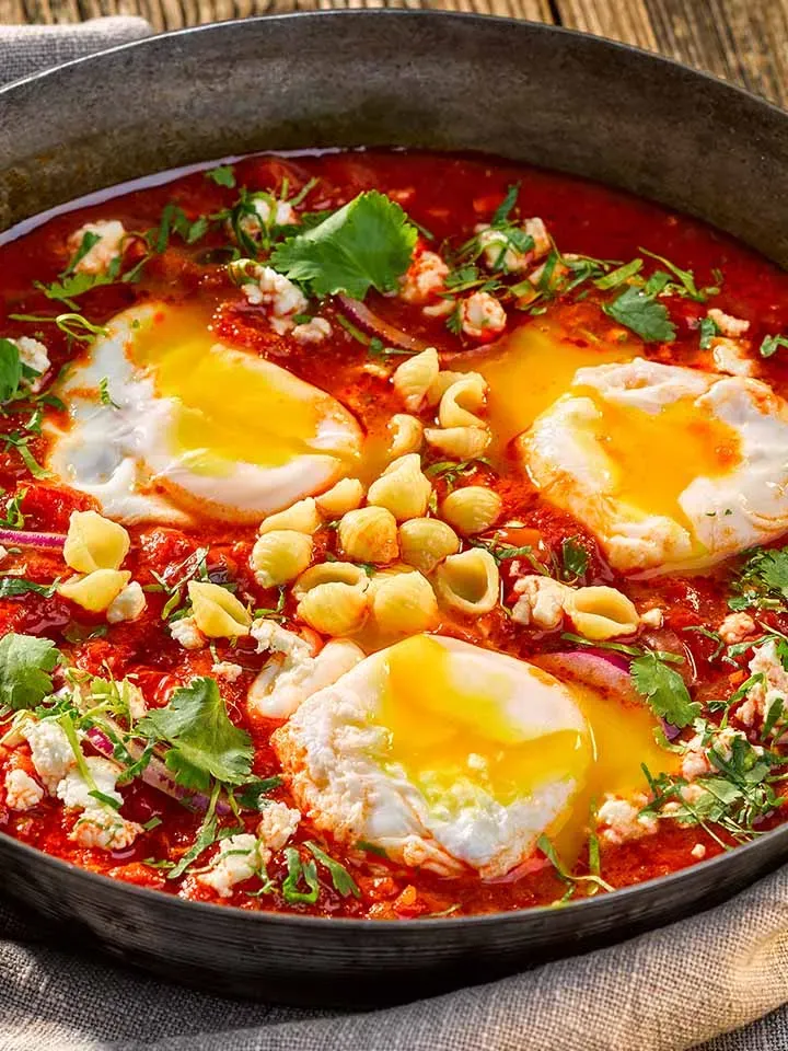 Shakshuka mit Schafskäse: Pfanne mit pochierten Eiern und frischen Kräutern