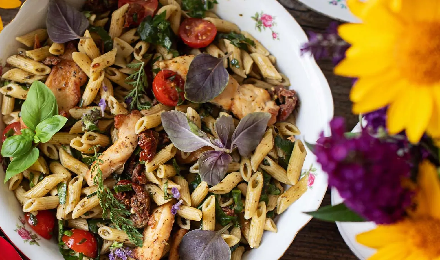 Sommernudelsalat mit zarten Hühnerfilets: Penne mit Hähnchen, Tomaten und frischen Kräutern auf einem Teller