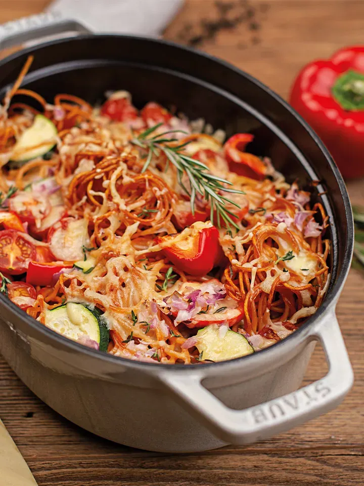 Spaghetti al Forno mit cremigem Gemüse und Ricotta gratiniert (Recheis) in grauem Bräter auf Holztisch