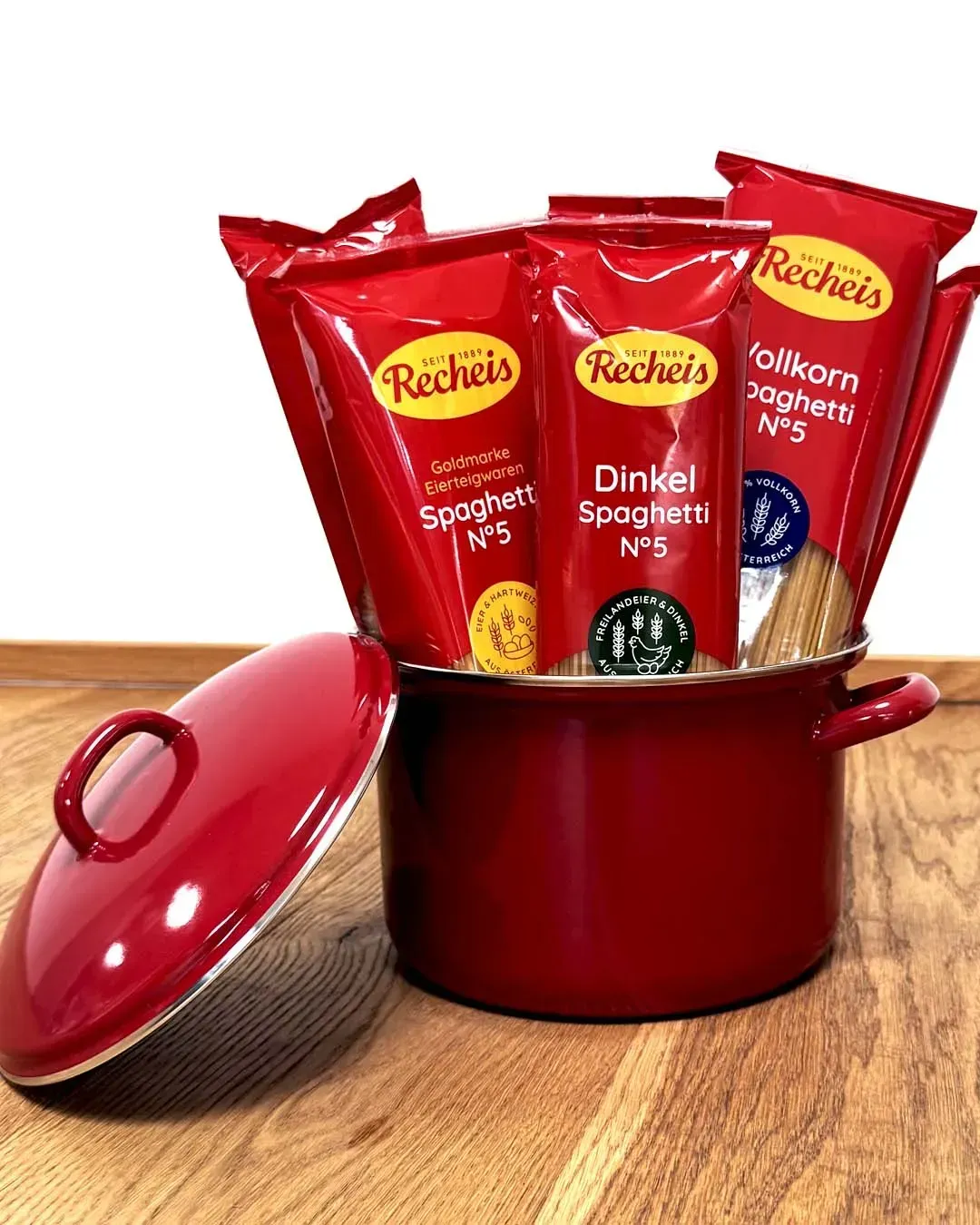 Roter Kochtopf mit Deckel, gefüllt mit verschiedenen Packungen Recheis Spaghetti