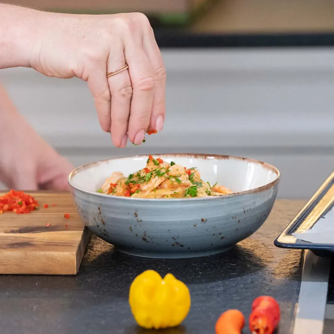 Hand streut gehackte rote Chilischoten über Spaghetti mit Ofenpaprikasauce in einer Schüssel, Anleitungsschritt 3