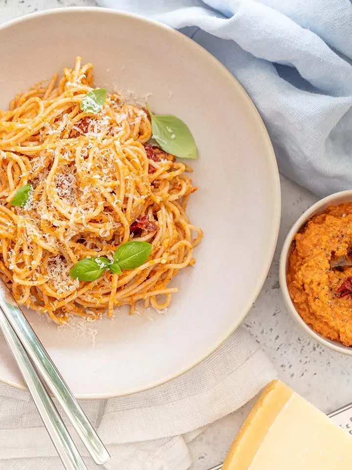 Spaghetti mit Pesto rosso, mit Basilikum und Parmesan auf einem Teller