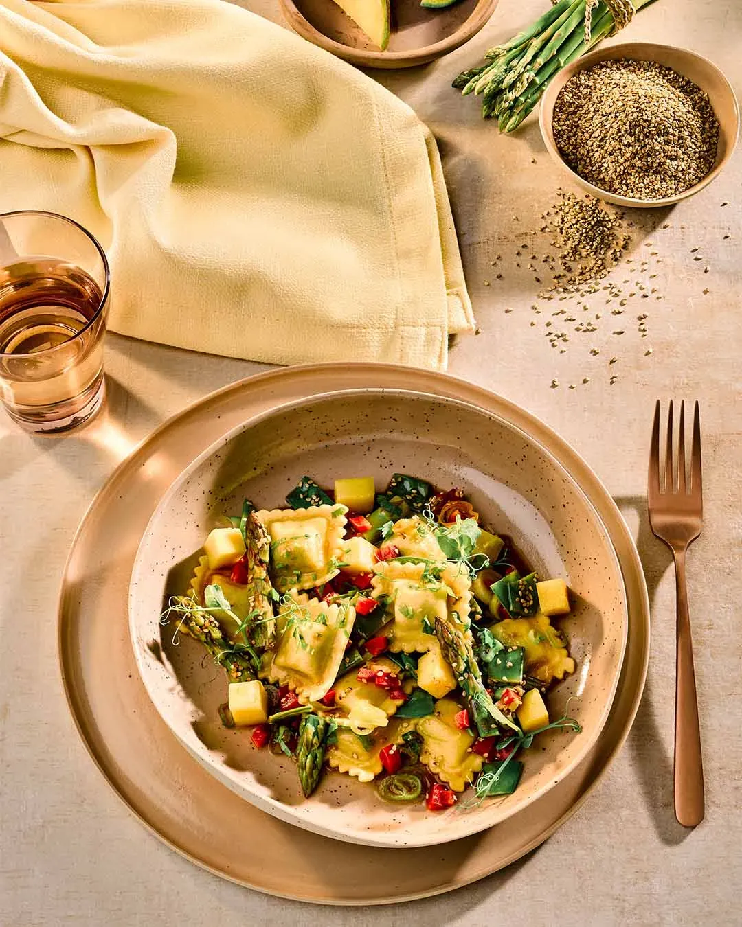 Spargeltortellini auf gedecktem Tisch mit Besteck und Glas