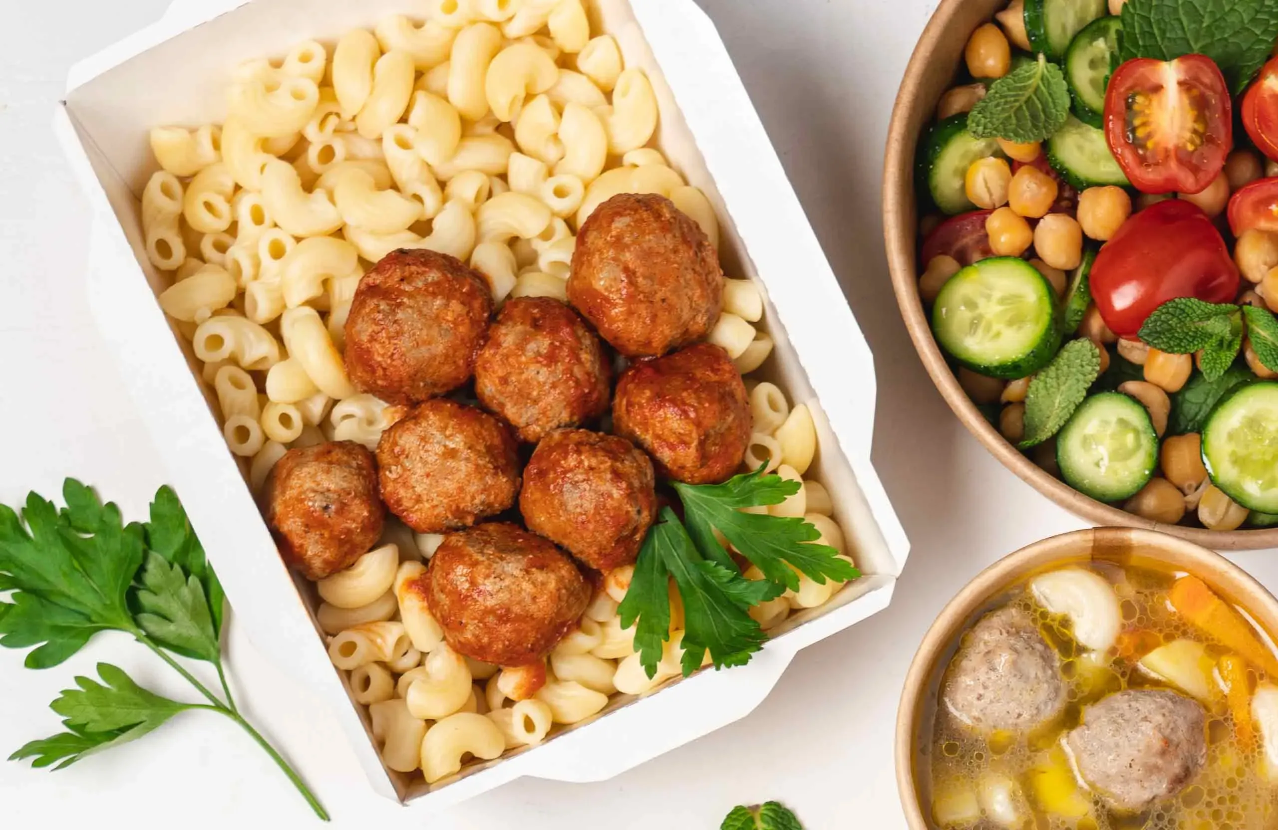 Nudeln mit Fleischbällchen und frischem Salat in Schalen angerichtet