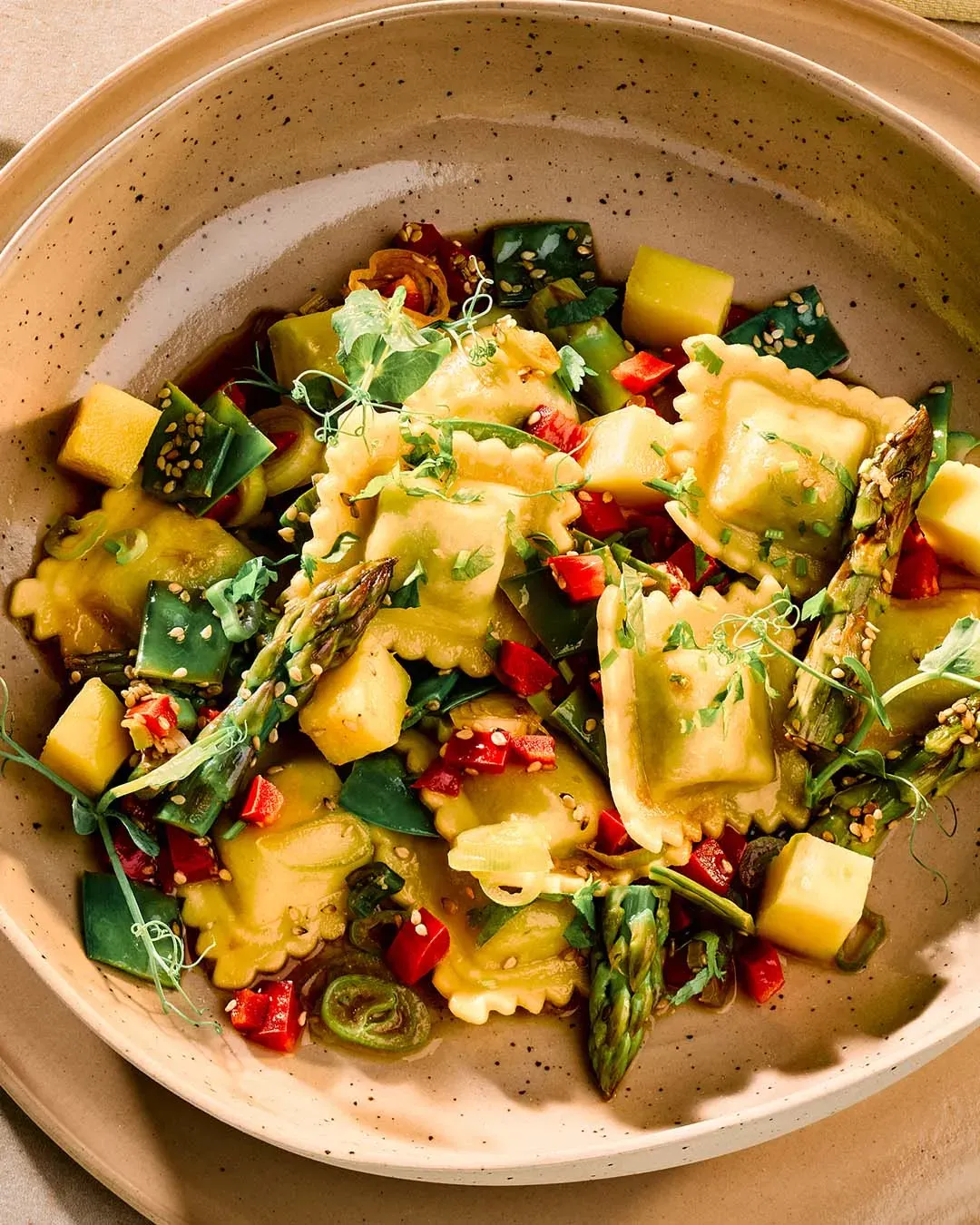Tortellini mit grünem Spargel, Paprika und frischen Kräutern auf Teller